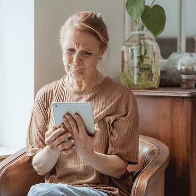 Elderly woman looking sad while viewing her tablet